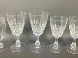 six empty wine glasses lined up on a table with a gray background