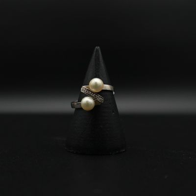 un gros plan d'une bague ornée de deux perles sur un cône noir