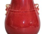 un vase rouge à deux anses sur fond blanc