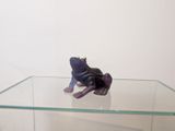 une petite figurine représentant une grenouille assise sur une étagère en verre