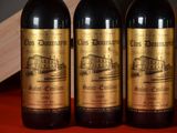 three bottles of red wine are lined up on a table