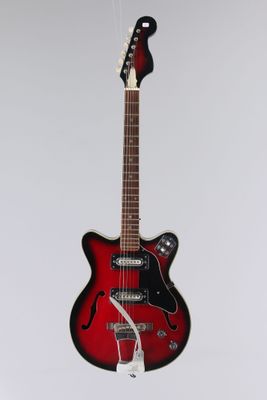une guitare électrique suspendue à une ficelle sur un mur blanc