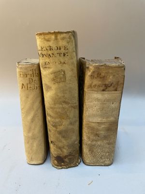 trois vieux livres posés l'un sur l'autre sur une surface blanche