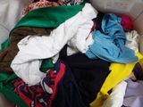 a pile of clothes in a box on a bed