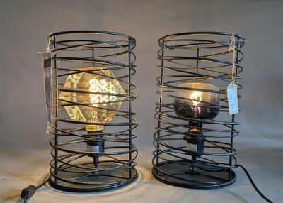 two metal lamps with a light bulb inside of them on a table