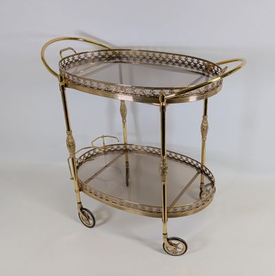 an antique brass bar cart with glass shelves on wheels