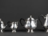 a group of four silver teapots and a coffee pot