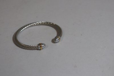 silver and gold bracelet on a white surface with a small bead
