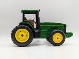 green toy tractor with yellow wheels on a white background