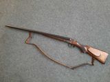 un fusil posé par terre, auquel est attachée une ficelle