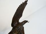 statue d'un aigle posée sur un socle en marbre, sur fond blanc