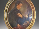 portrait of a man in a black coat holding a skull in a gold frame