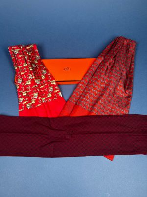 two pairs of red and gold patterned pants and a red scarf on a blue background