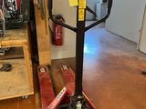 a red dolly truck with a black handle in a room