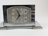 a silver clock that is sitting on top of a table