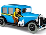 une petite voiture bleue dans laquelle se trouvent un homme et un chien