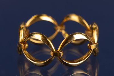 une image montrant un gros plan d'une bague en or posée sur une surface bleue