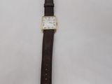 a close up of a watch on a white surface with a brown strap