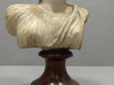 a white marble bust of a woman on a wooden base