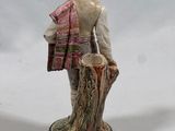 figurine of a man with a hat and scarf standing on a stump