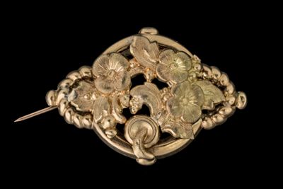 broche en or jaune représentant des fleurs et des feuilles sur fond noir