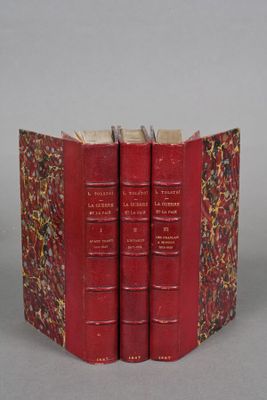 three red books are stacked on top of each other on a gray surface