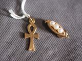 gold ankht and pearl pendants on a gray cloth