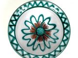 a blue and white plate with a red flower on it