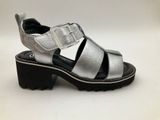 silver sandals with black soles and buckles on a white background