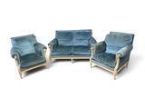three blue velvet chairs and a couch in a white room