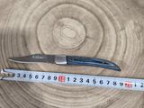 a measuring tape on a piece of wood with a knife on it