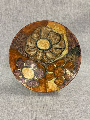 une assiette marron ornée d'une fleur, posée sur une table