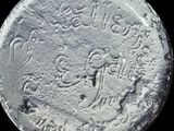 an old silver coin with writing on it on a black background