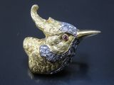 une image représentant une broche en forme d'oiseau en or et diamants sur un fond noir