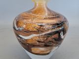 a glass vase that has a brown and white swirl on it