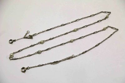 deux colliers à chaîne en argent posés sur une surface blanche, sur fond blanc