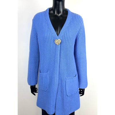 Le pull est bleu et est orné d'une broche dorée.