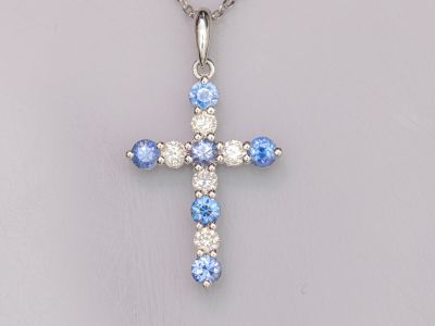 un gros plan d'une croix ornée de pierres bleues et blanches, suspendue à une chaîne