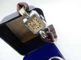 a watch with a chain around it sitting on top of a blue box