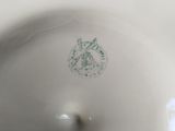 a close up of a white plate with a green emblem on it