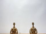 pair of antique brass candlesticks on wooden table against white wall