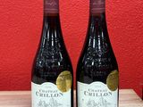 two bottles of wine sit on a table in front of a red wall