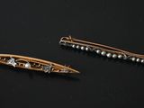 pair of gold tone hair pins with pearls on a black background