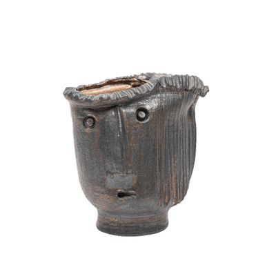 un vase noir orné d'un visage sur fond blanc