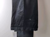 black pants hanging on a hanger against a white wall