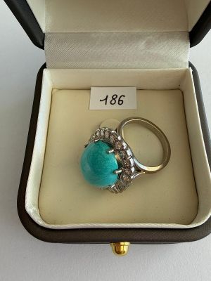 une image représentant une bague dans un écrin, sertie d'une pierre turquoise