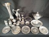 a lot of silver plates and silver vases on a table