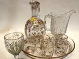Des bouteilles et des verres sont posés sur un plateau, avec une carafe en arrière-plan.
