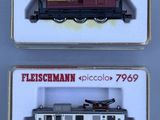 Deux trains miniatures sont exposés dans une vitrine posée sur une table