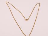 un collier à chaîne en or orné d'un seul diamant sur fond blanc
